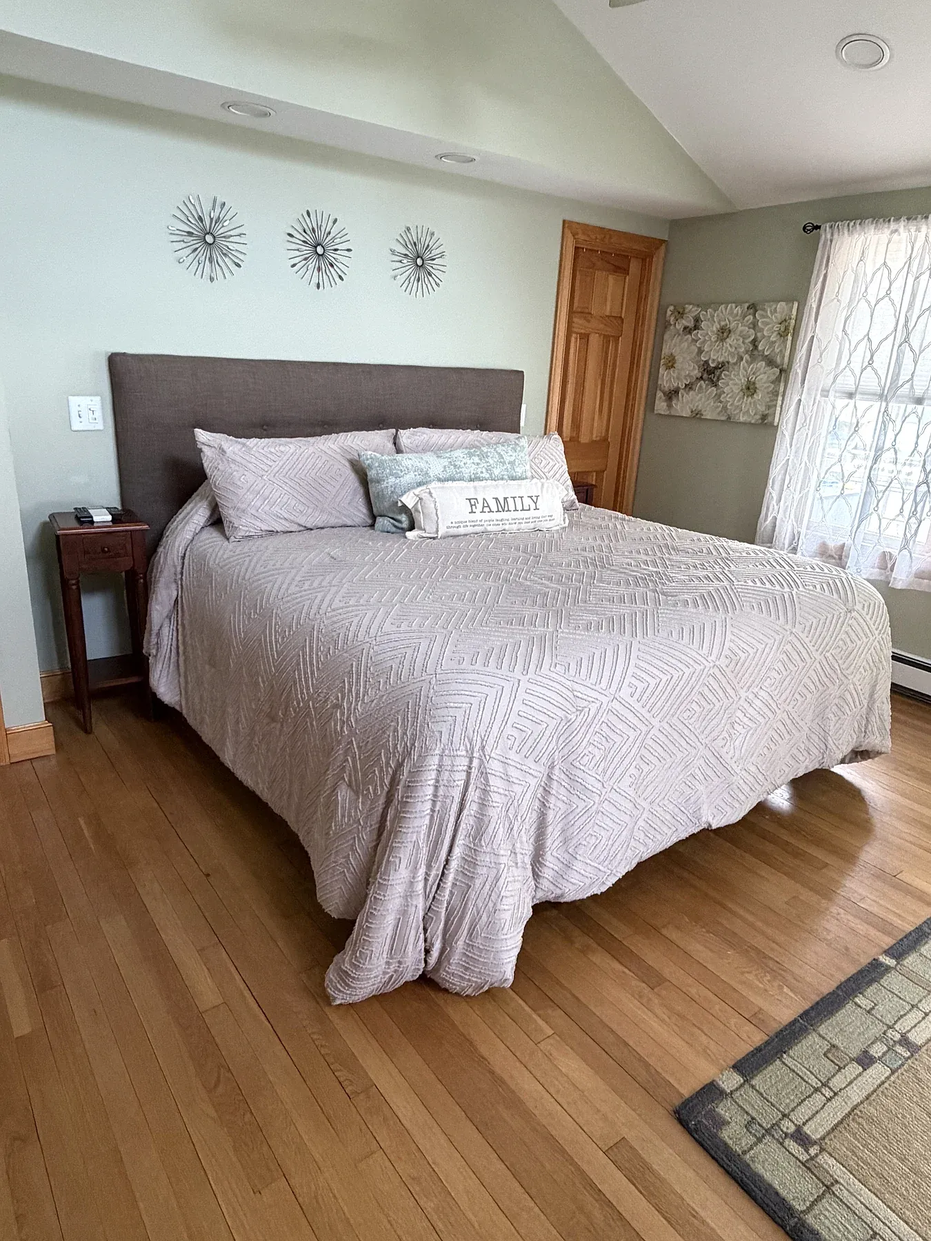A guest bedroom with fresh bedding, clean wood floors and bedside tables.