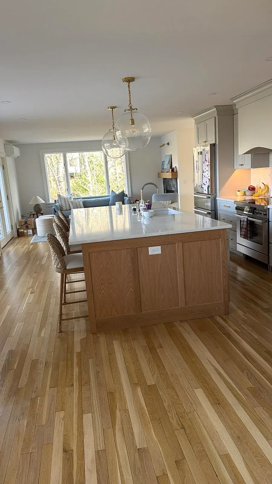 A clean kitchen island with a sink, wood floor and daylight through the windows.